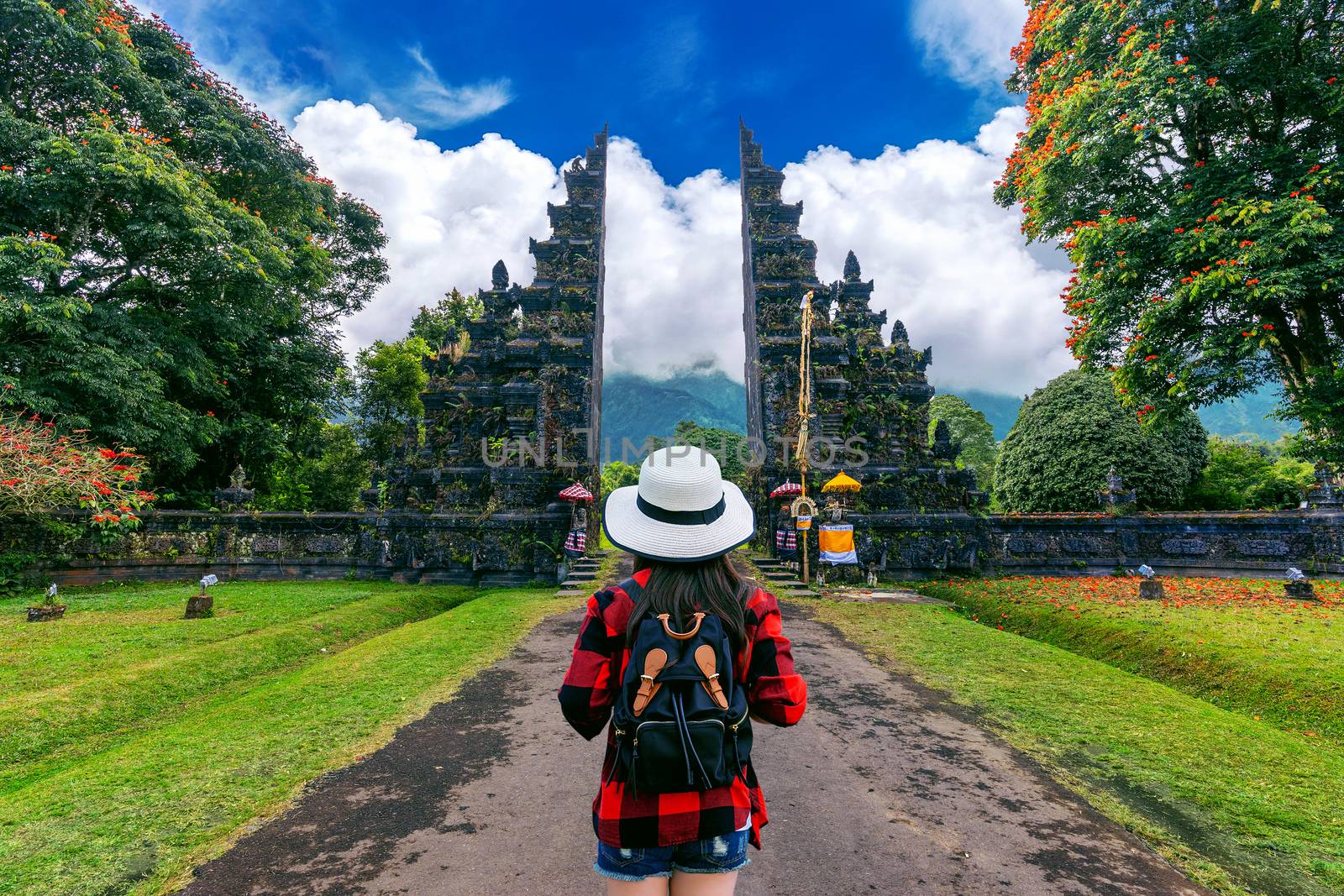 Woman traveler with backpack walking at Big entrance gate in Bali, Indonesia.
