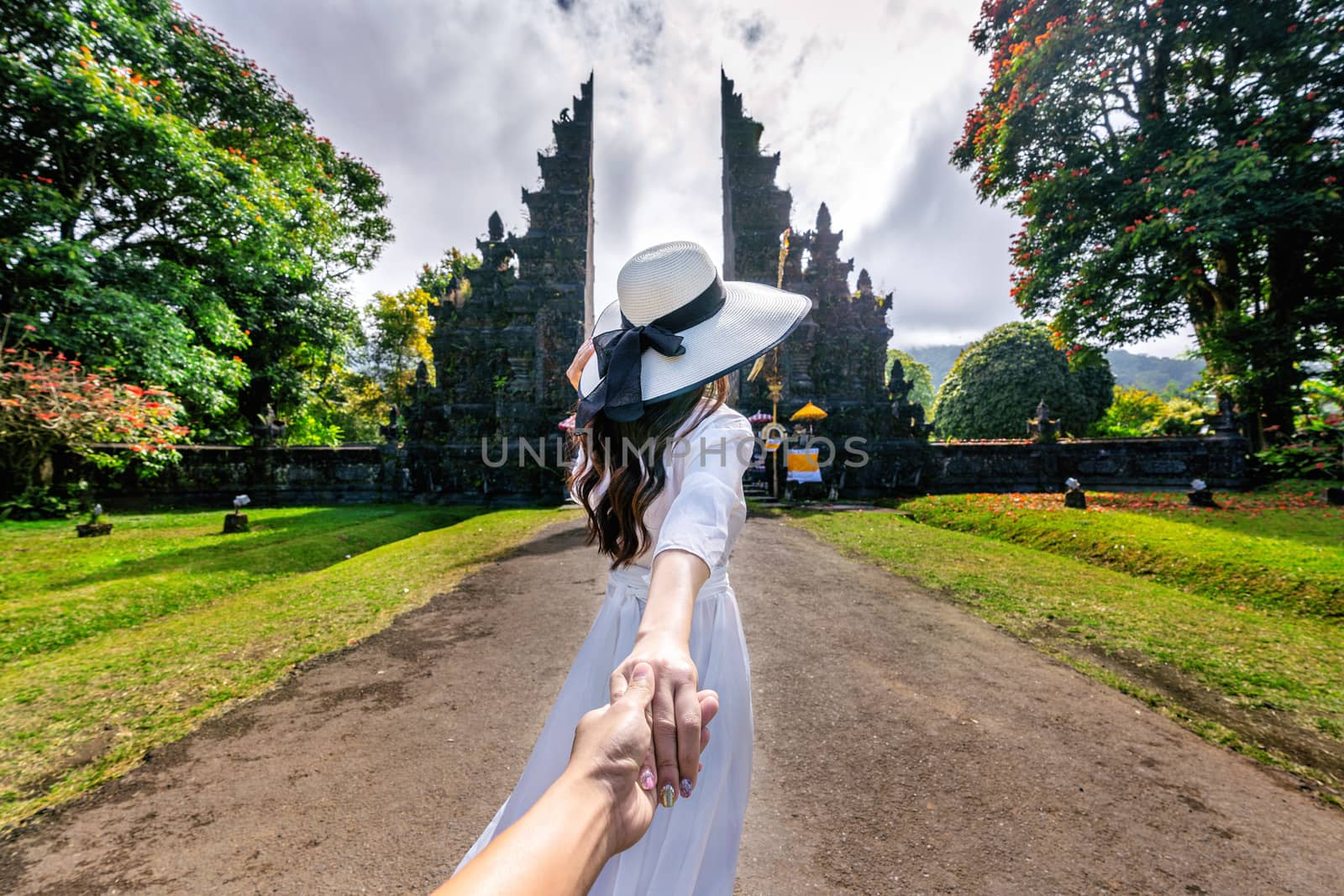 Women tourists holding man's hand and leading him to Big Gate in Bali, Indonesia.