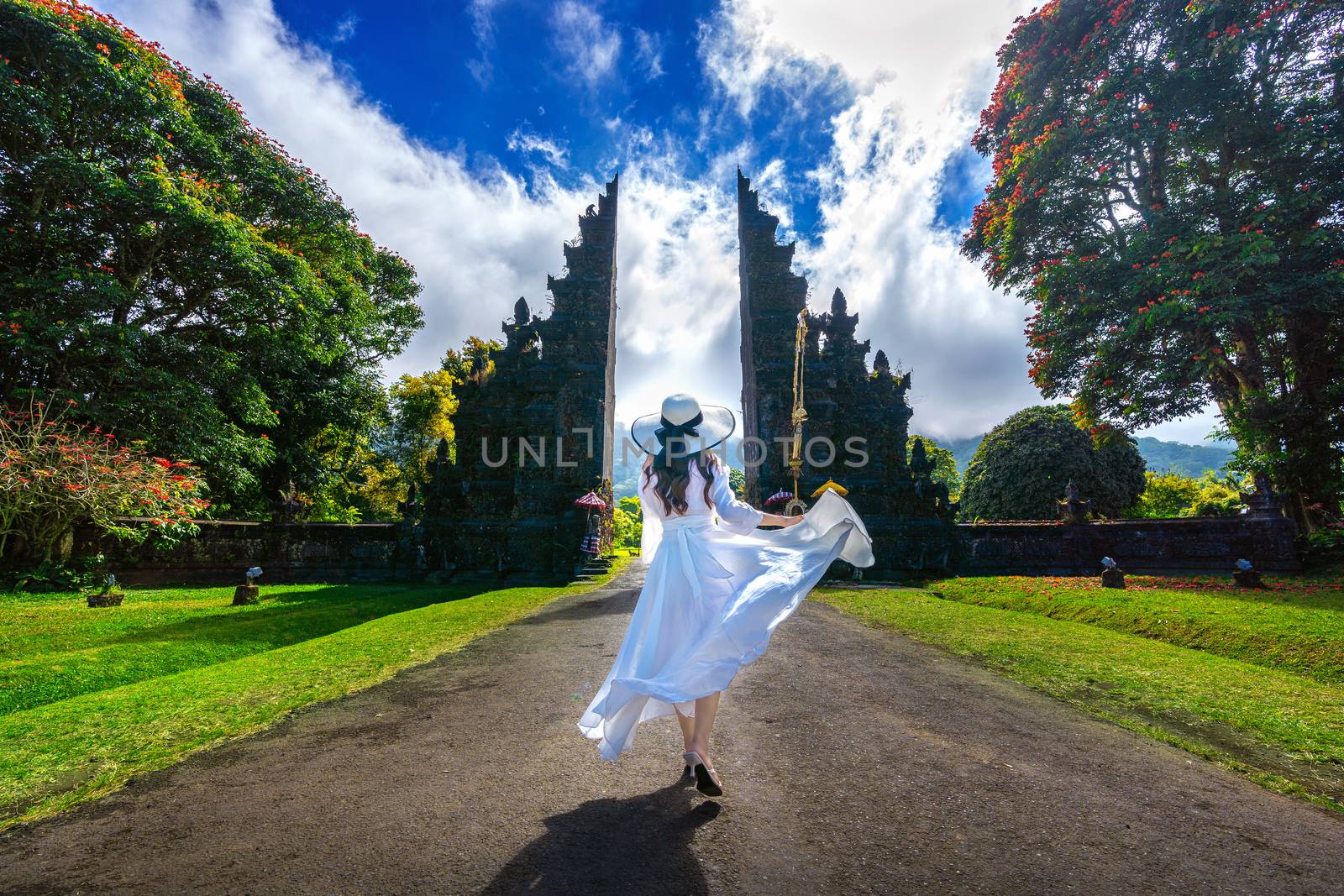 Woman walking at big entrance gate, Bali in Indonesia. by gutarphotoghaphy