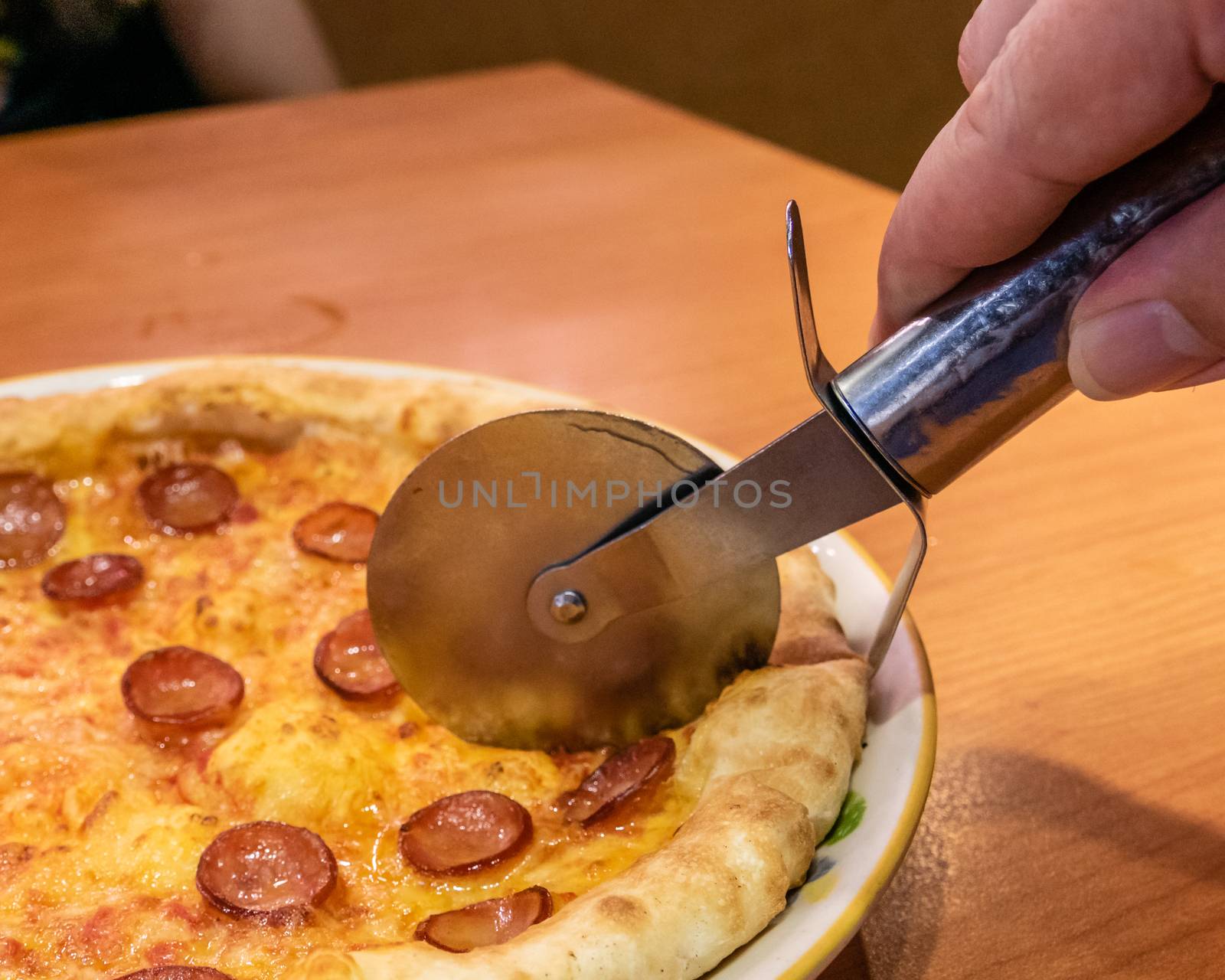 Cutting chorizo sausage pizza with cheese in plate