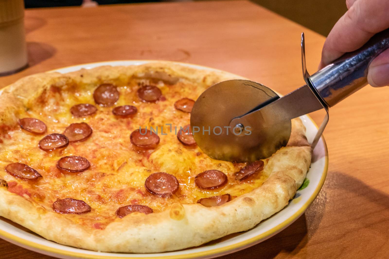 Cutting chorizo sausage pizza with cheese in plate