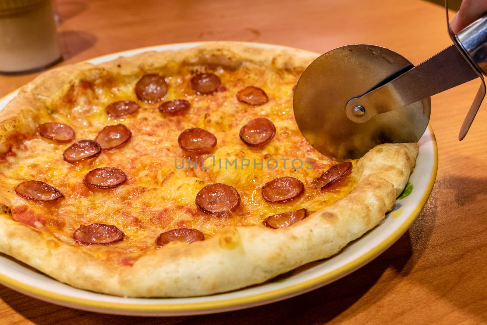 Cutting chorizo sausage pizza with cheese in plate