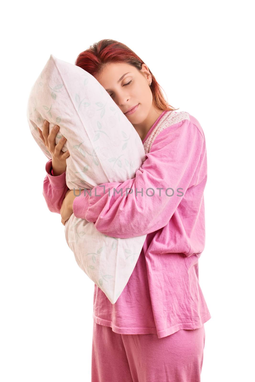 My comfortable pillow. Beautiful young girl in pink pajamas with closed eyes hugging a pillow, isolated on white background.