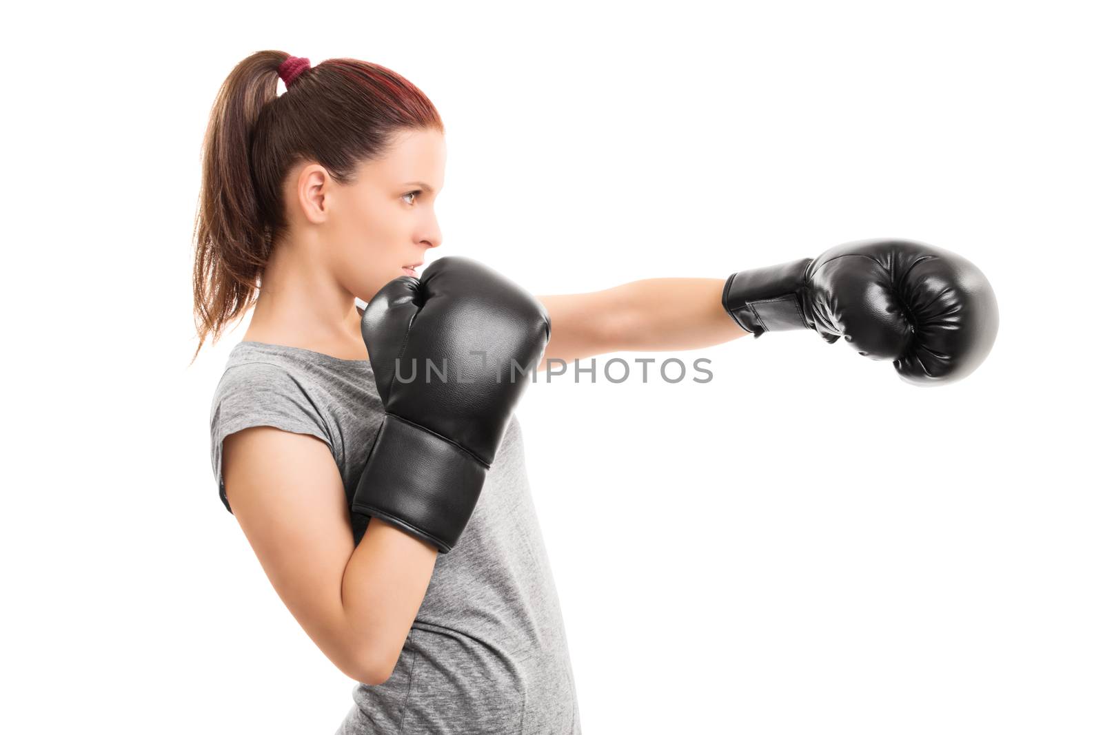 Profile shot of a beautiful young girl with boxing gloves punching, isolated on white background.