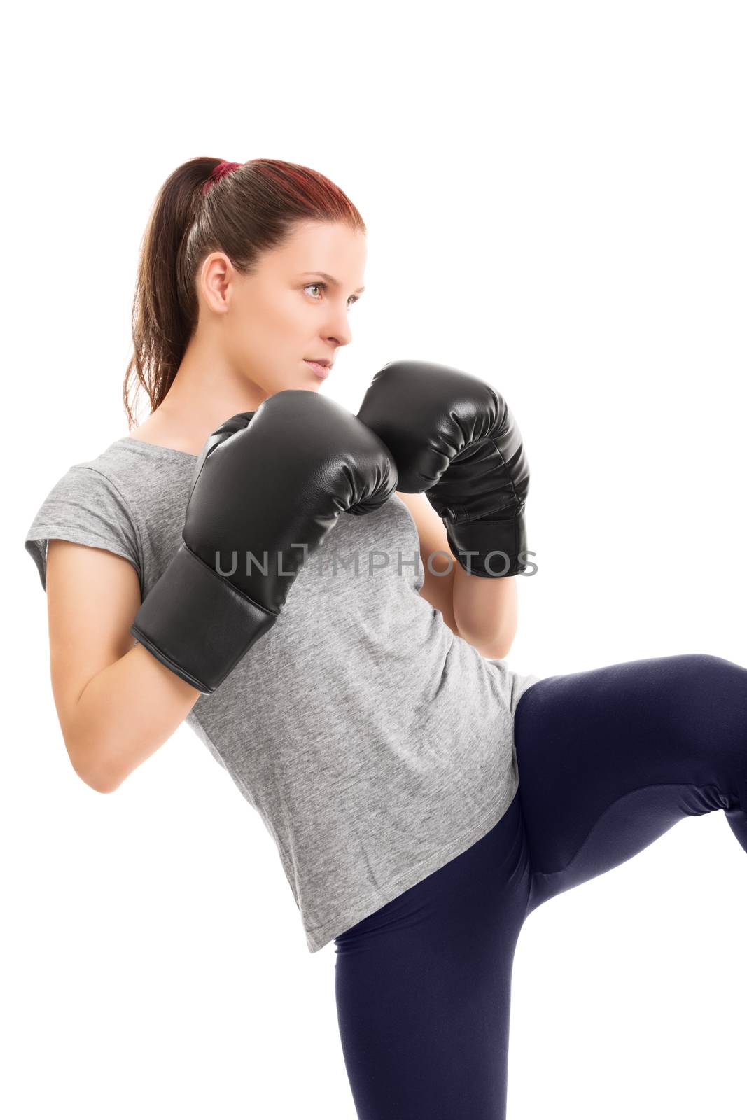 A profile of a beautiful young girl with boxing gloves delivering a kick, isolated on white background.