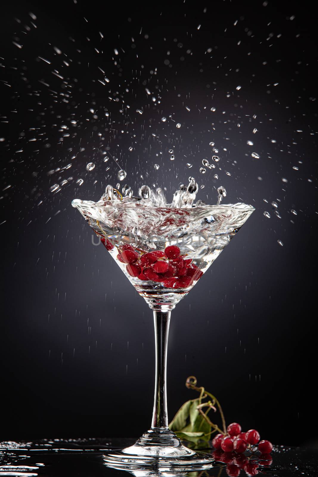 Bunch of red currant falling into the glass of water