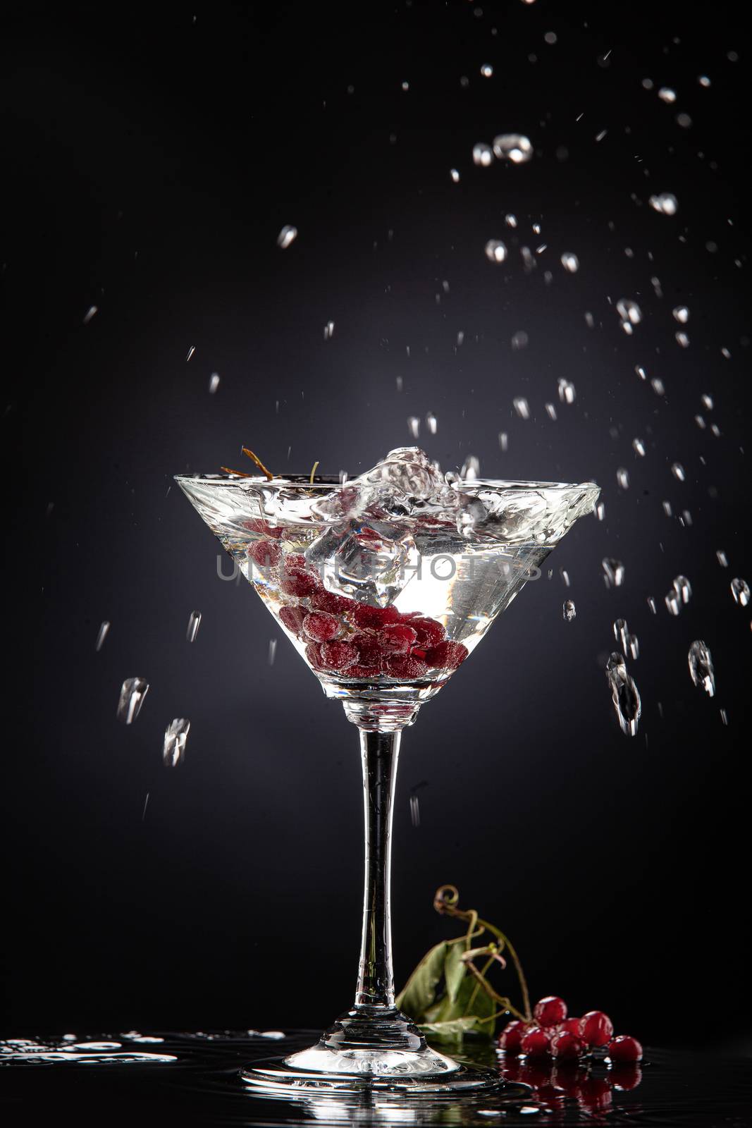 Bunch of red currant falling into the glass of water