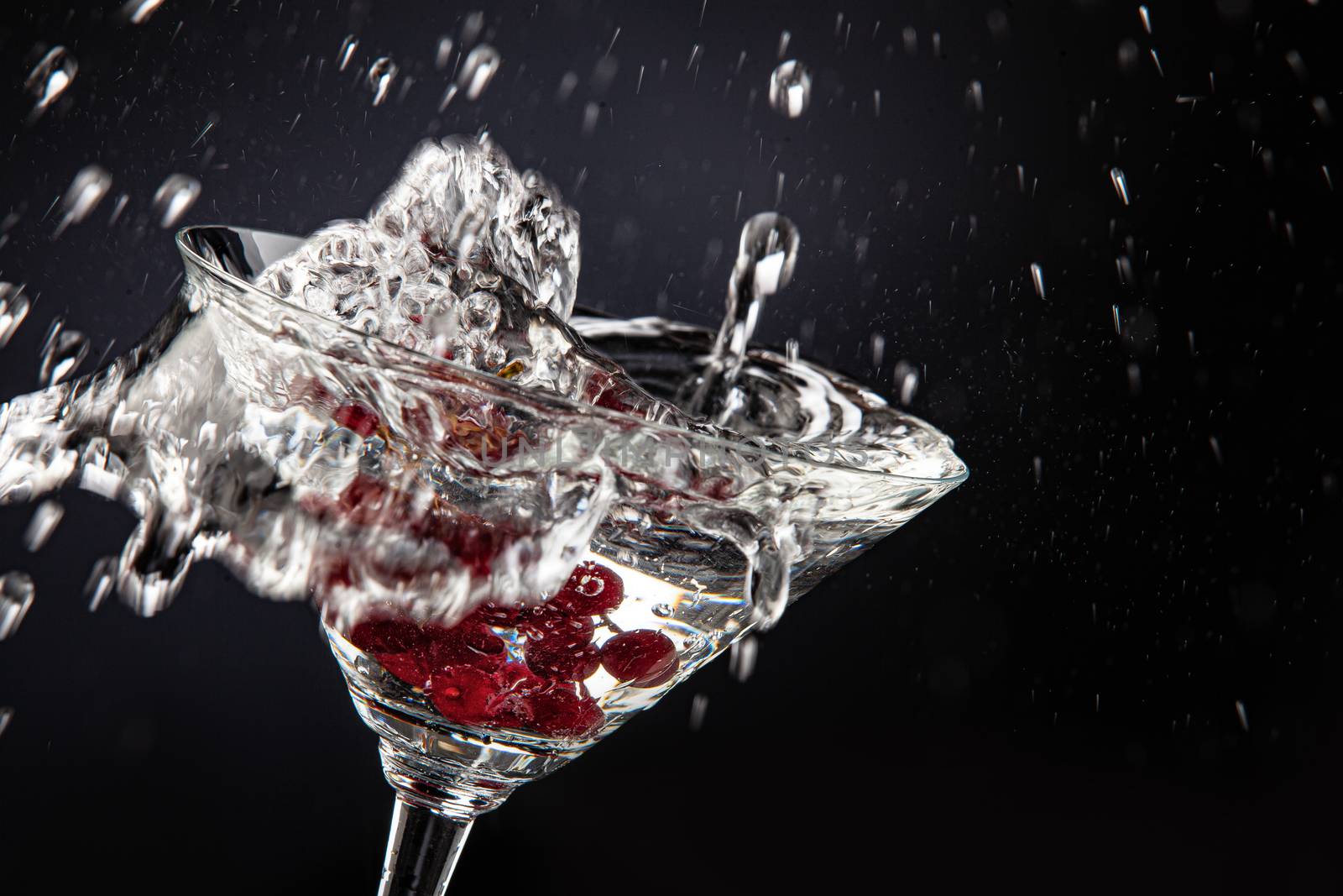 Bunch of red currant falling into the glass of water