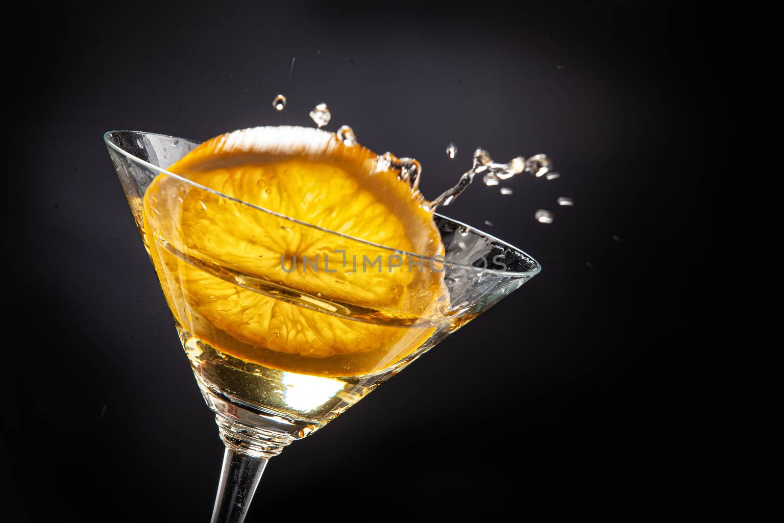 Slice of orange falling into the glass of juice