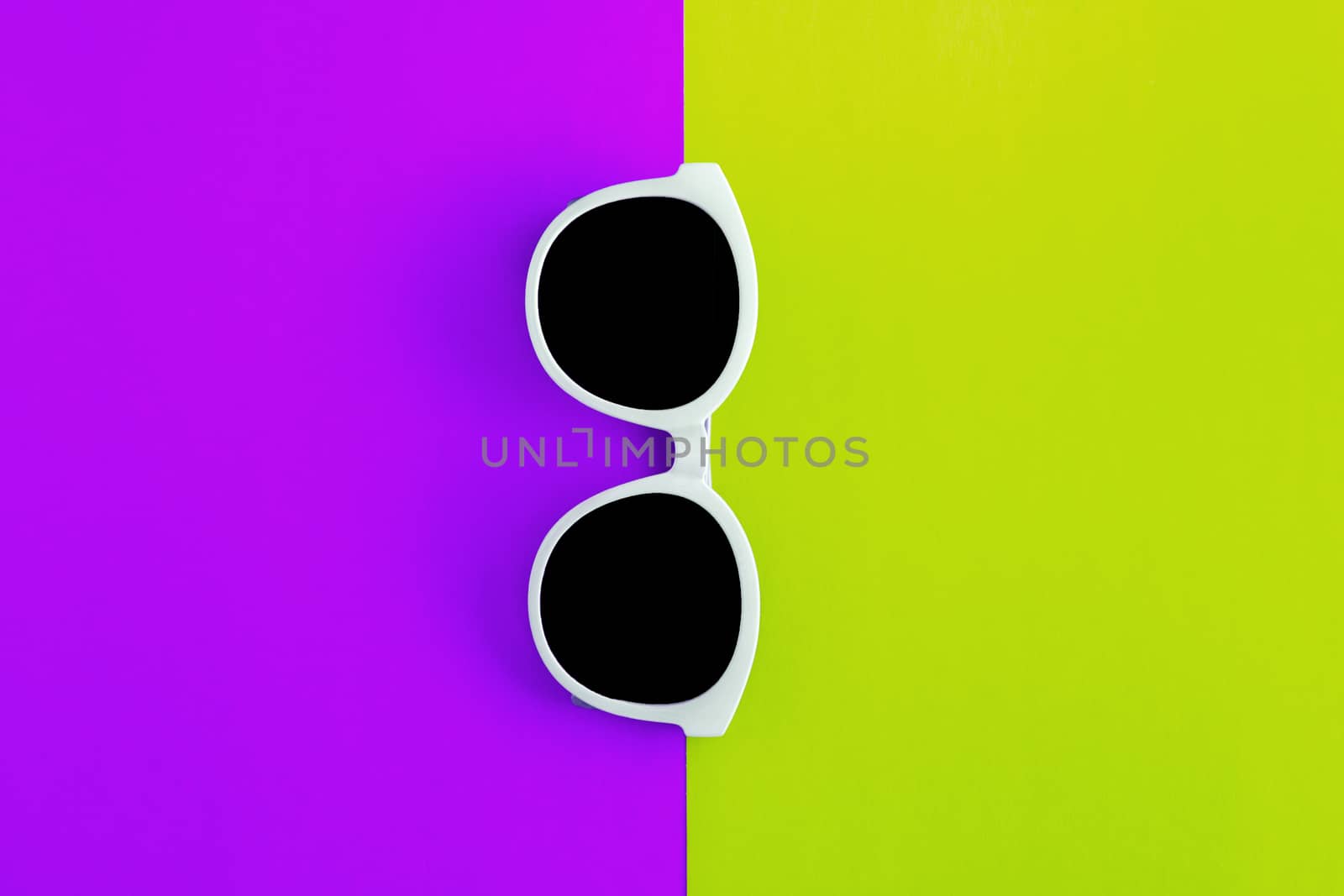 Sunny stylish white sunglasses on a bright purple-lilac and yellow-green background, top view, isolated. Copy space. Flat lay.