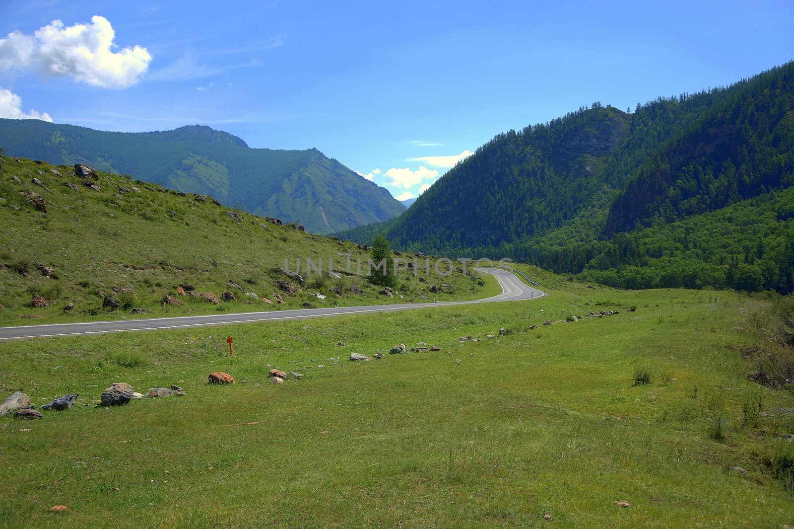 Asphalt road running through a mountain field valley. Chuysky tract, Altai, Siberia, Russia.