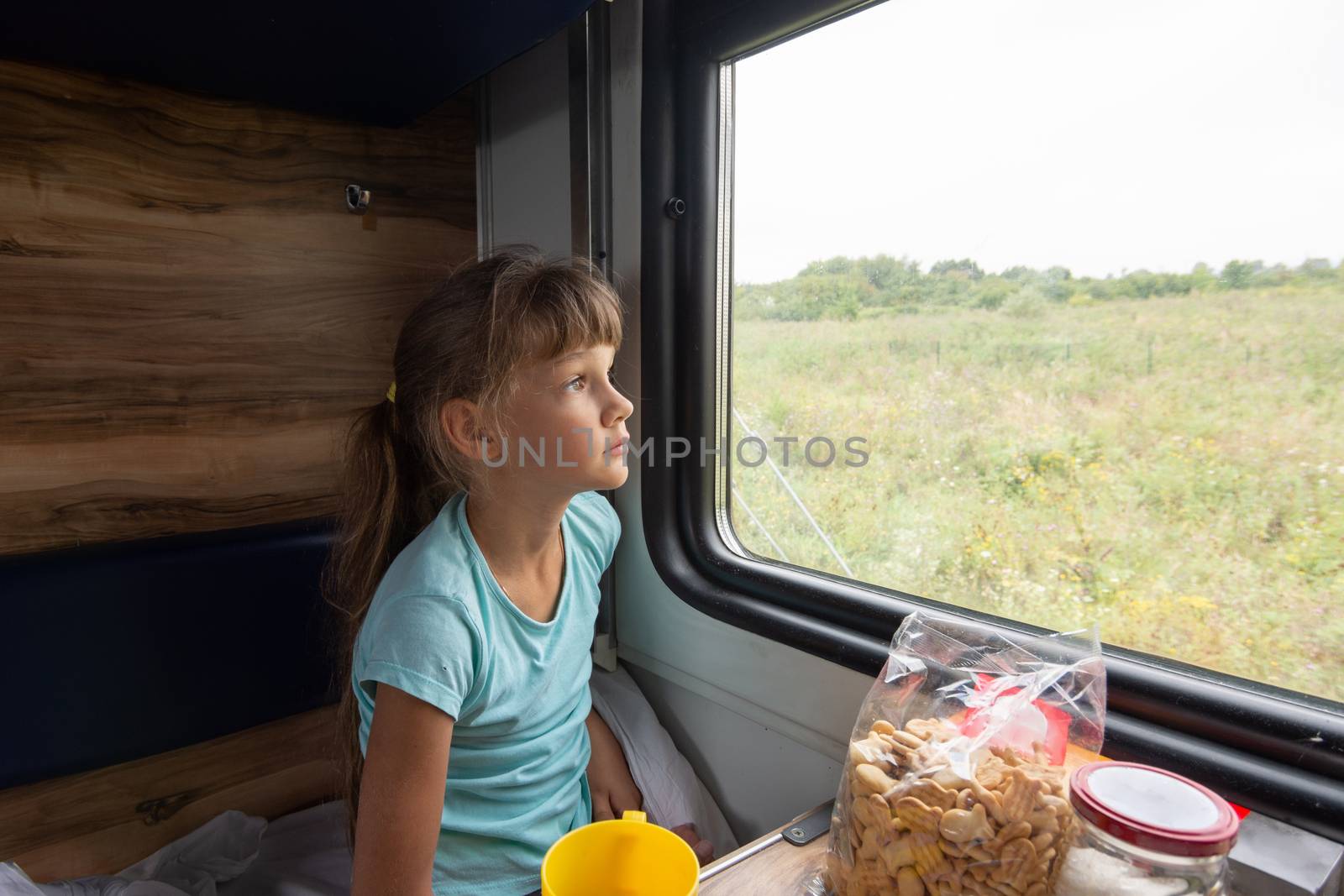 Girl sitting in a reserved seat wagon looks tiredly out the window