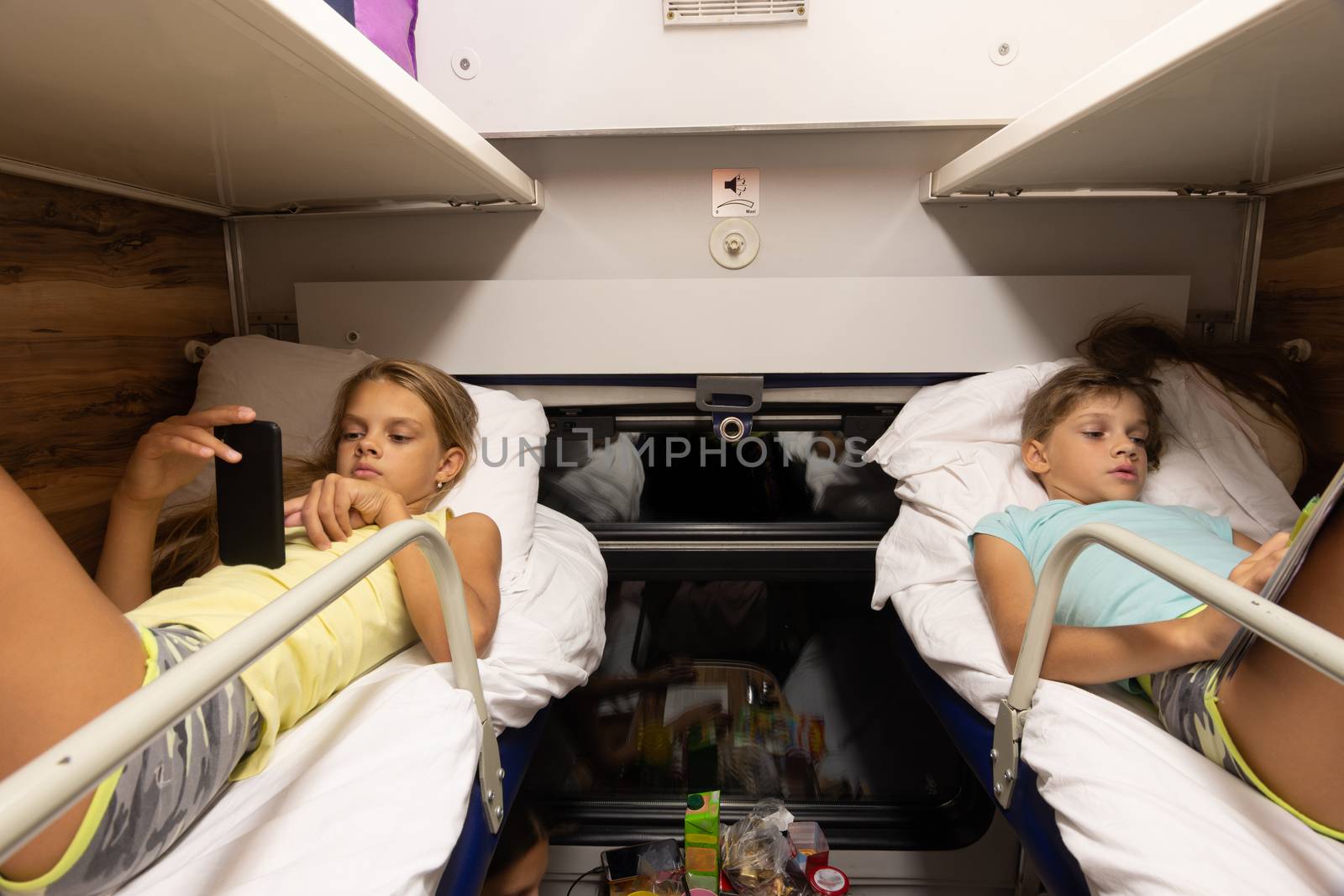 Children on the upper shelves of a reserved seat car do different activities