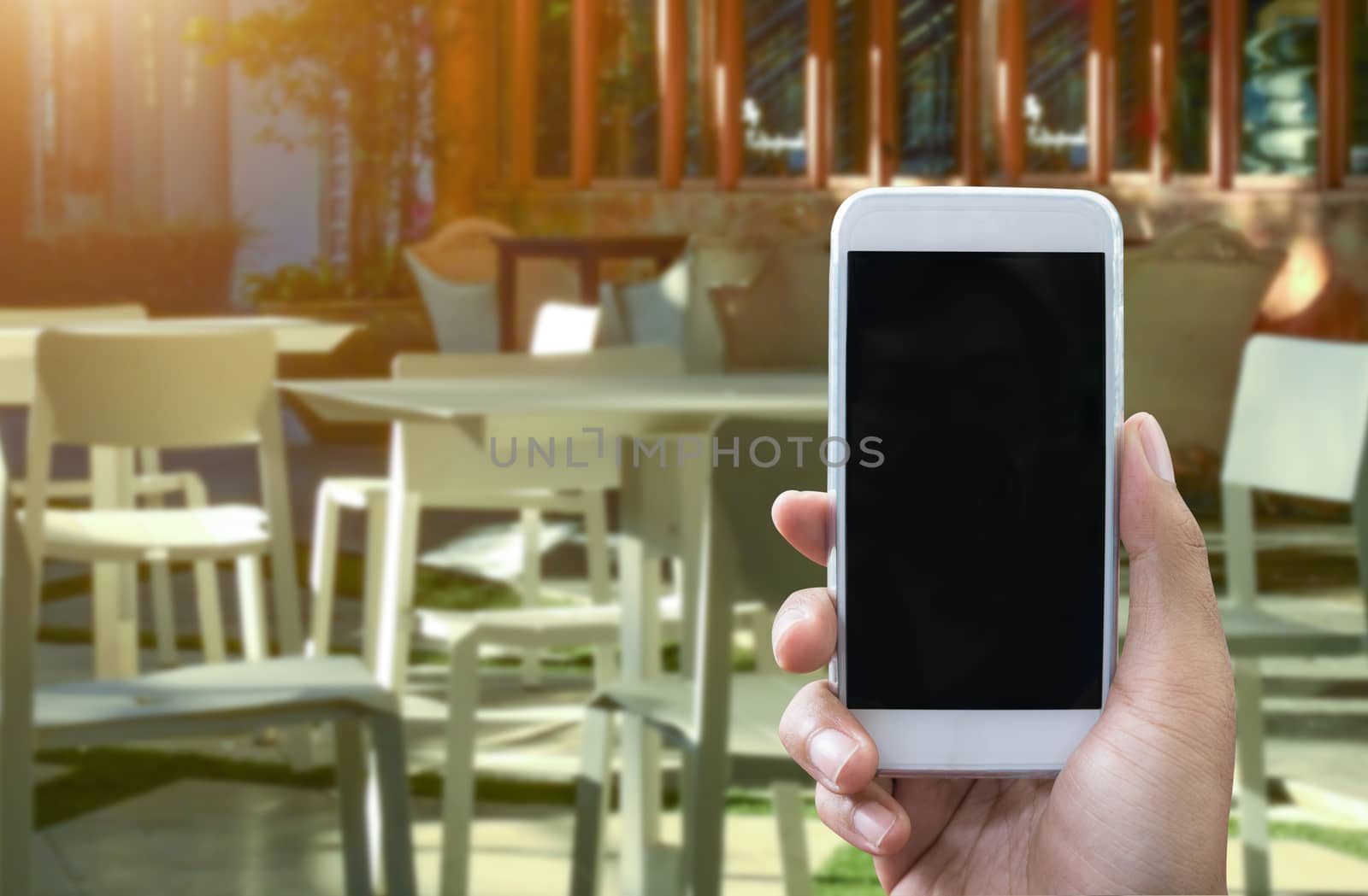 Man's hand shows mobile smartphone in vertical position and blurred background - smartphone mockup template