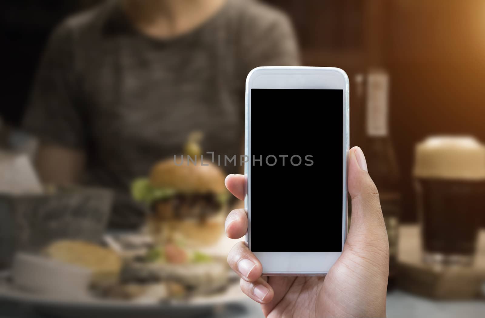Man's hand shows mobile smartphone in vertical position and blurred background - smartphone mockup template