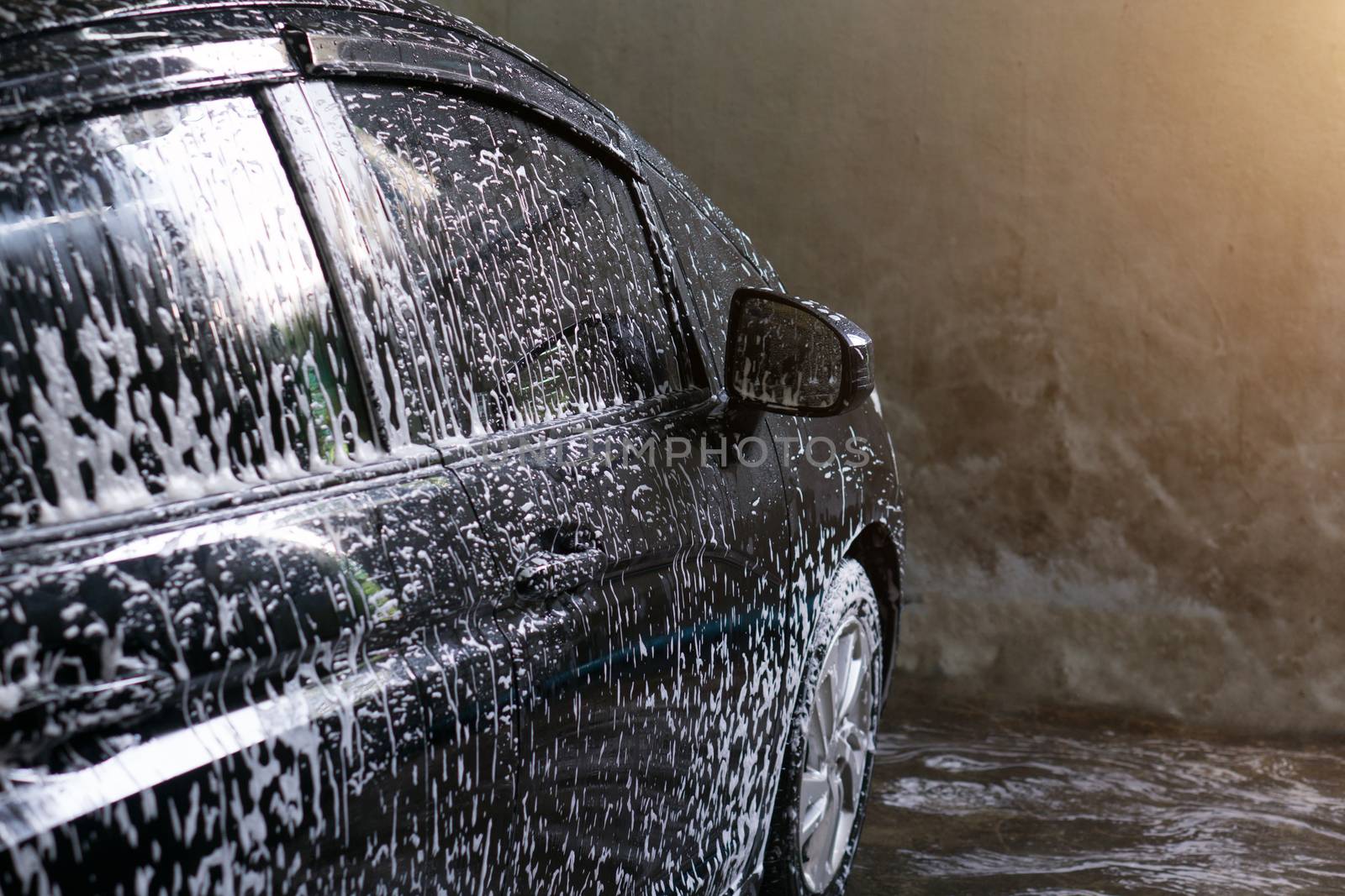 Selective focus of Black Car wash with soap and sunlight filter effect