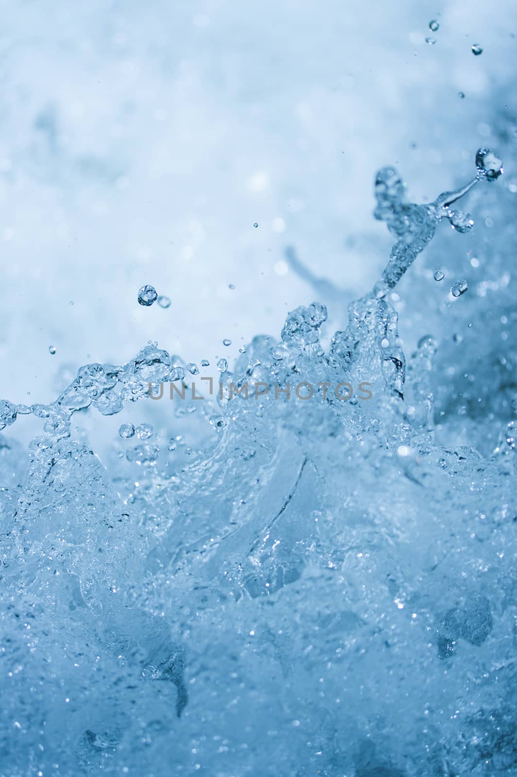 Blue water splash background from nature waterfall in rainforest. Portrait position.