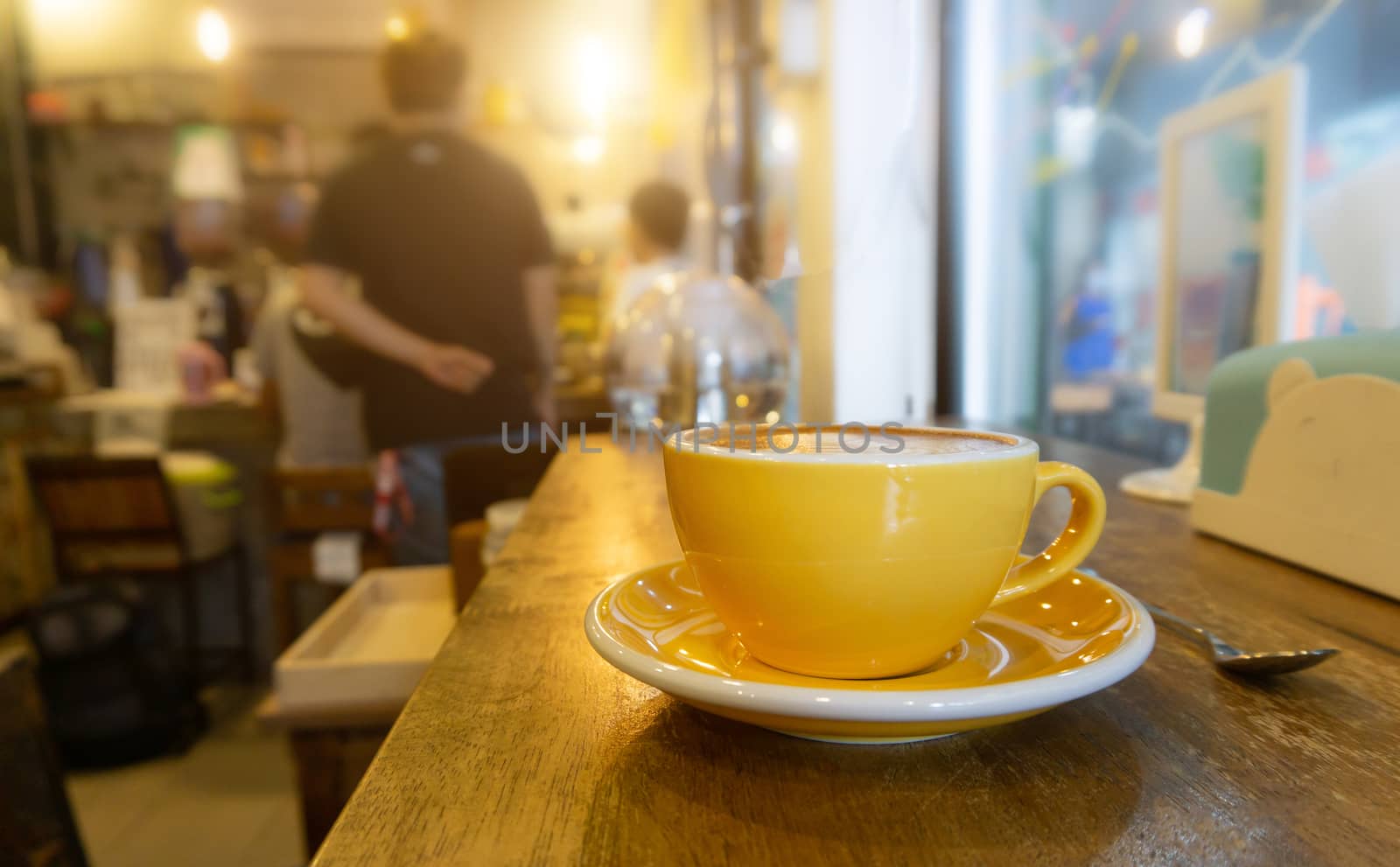 Coffee in yellow coffee cup and on a wood background.