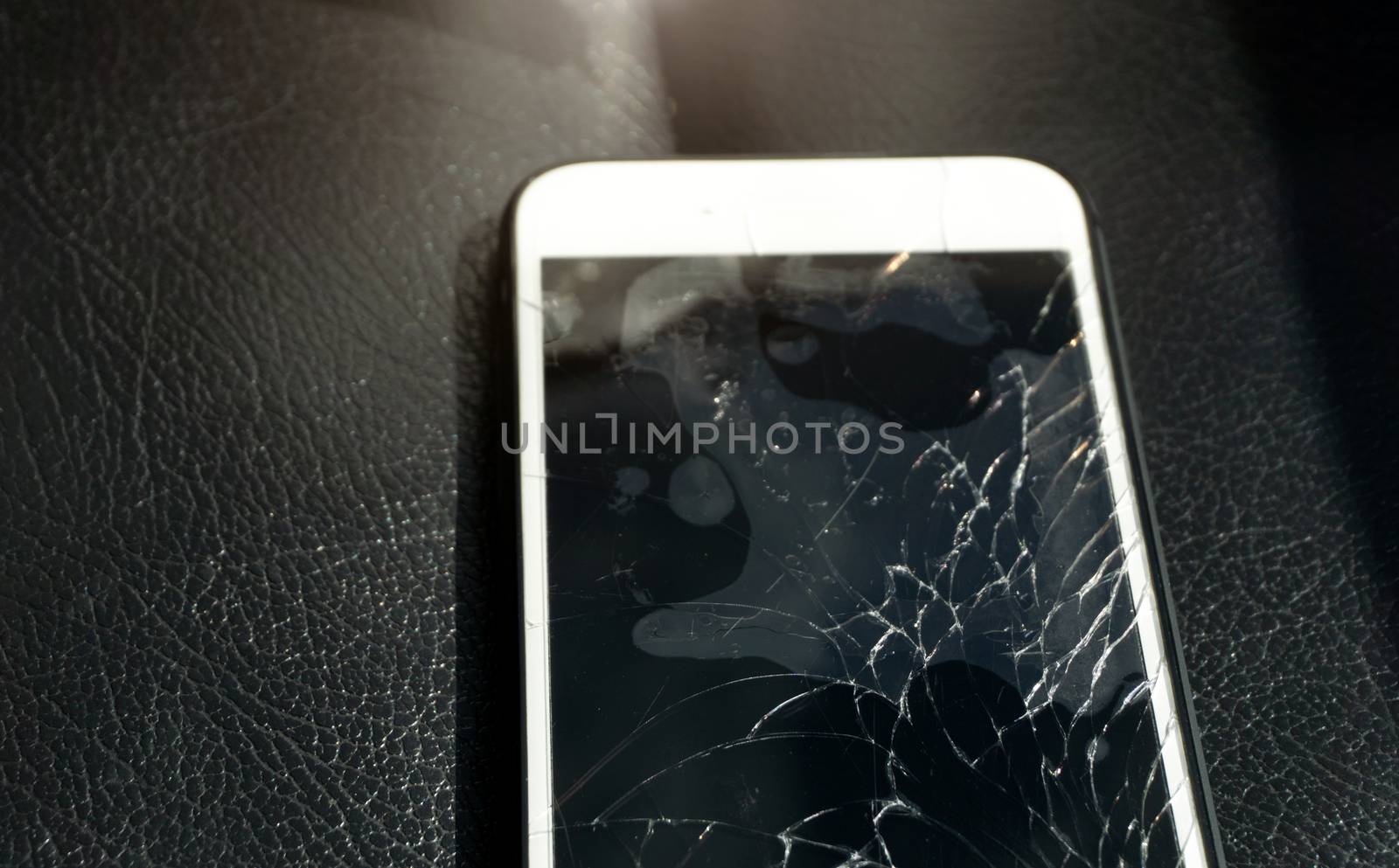 Close up of cracked smartphone screen lay on black leather by pkproject