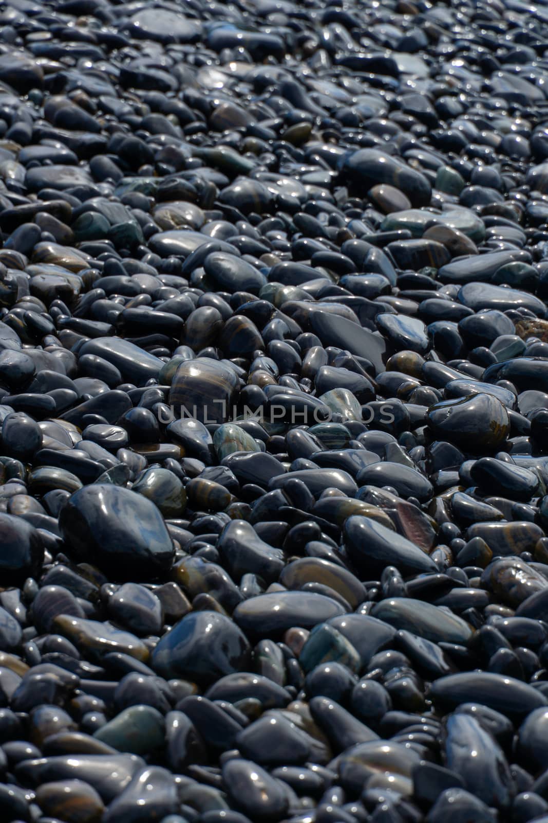 Wet Black pebble stones island in Koh hin ngam, Tarutao National Park, Satun, Thailand.