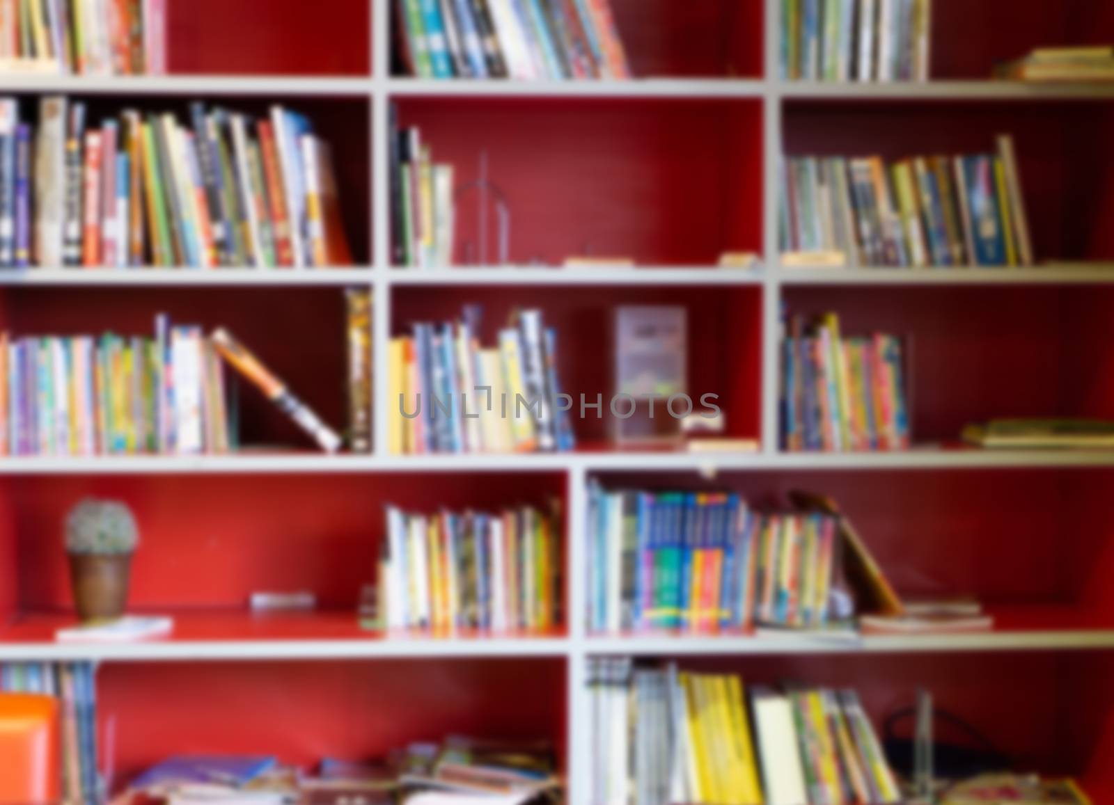 Blurred red bookshelf with many books in library for  education Concept background.