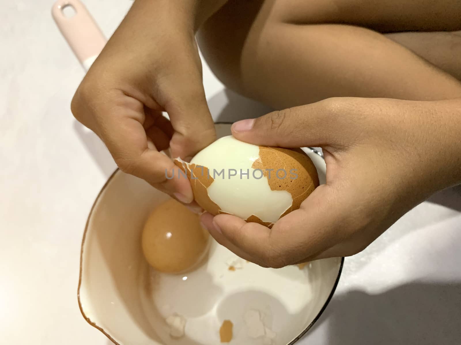 Little Asian boy is peeling boiled egg.