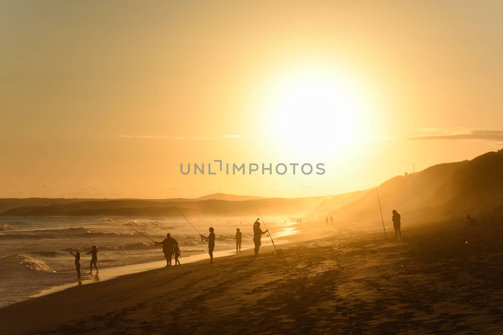 Family vacation with fishing rods on beach at sunset, Mossel Bay, South Africa