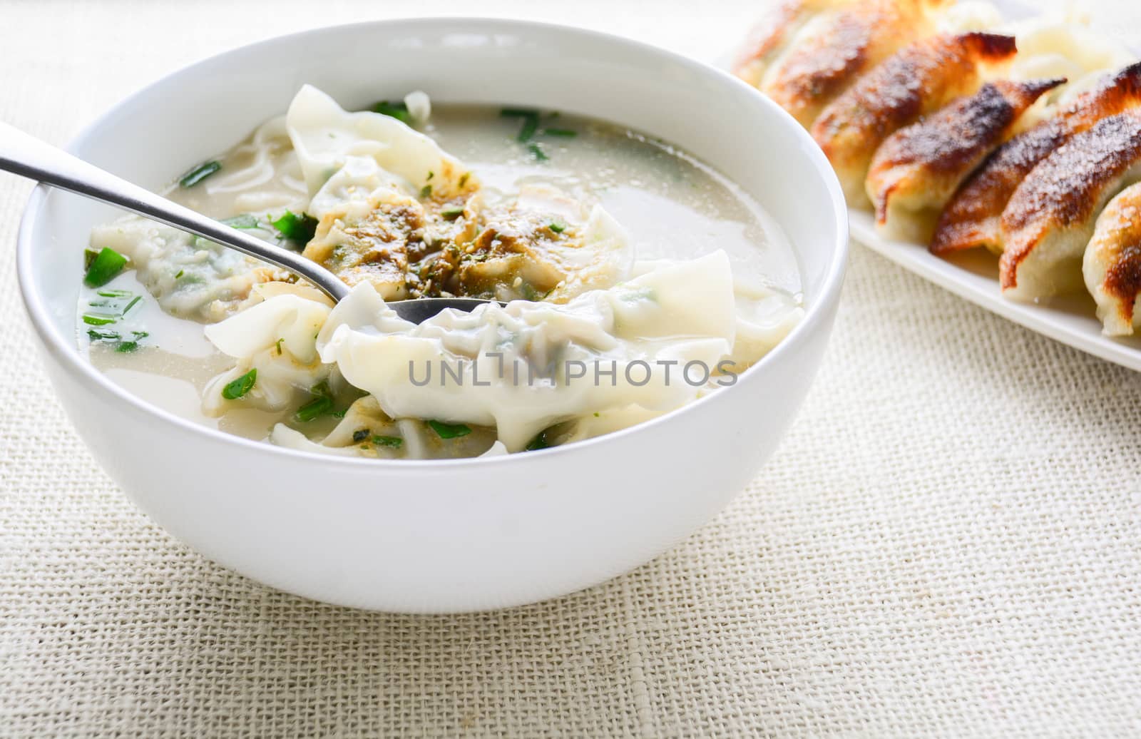 Wonton soup with spring onion served in a white bowl, selective  by yuiyuize