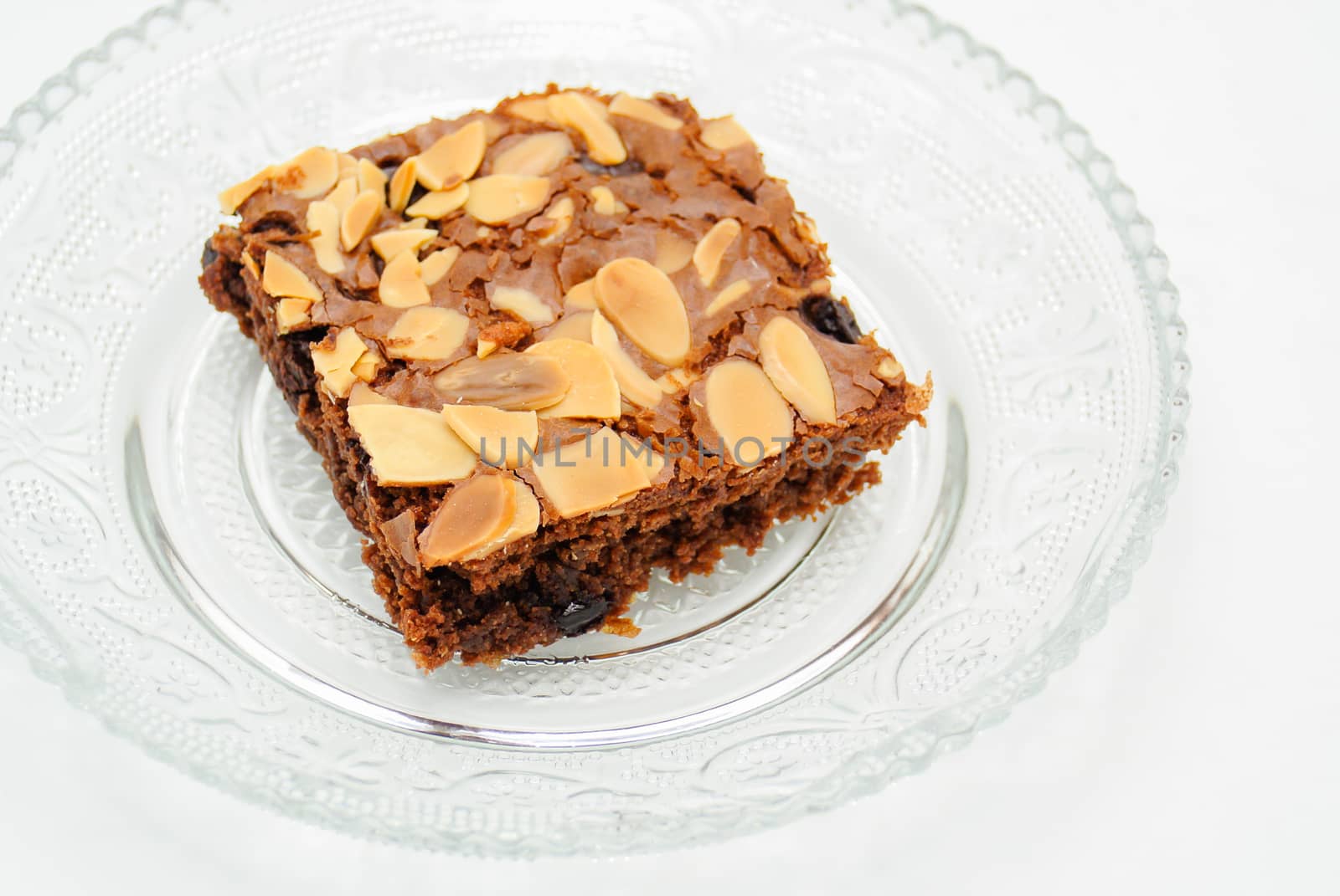 Chocolate brownie with almond topping on glass plated
