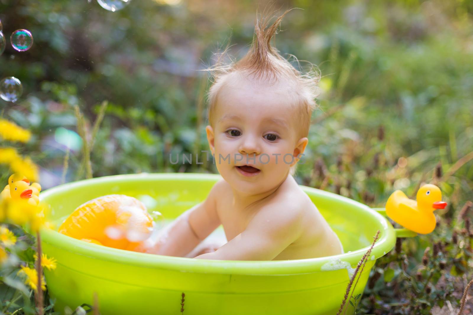 Toddler boy in basin taking a bath with bubbles and duck toys ou by Angel_a