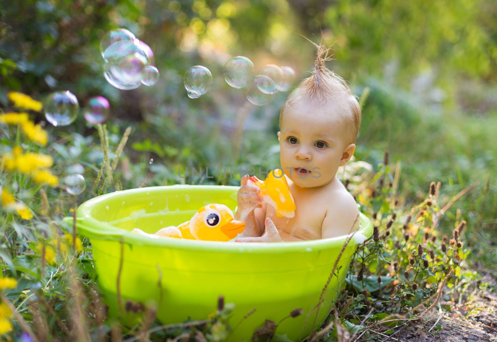 Toddler boy in basin taking a bath with bubbles and duck toys ou by Angel_a