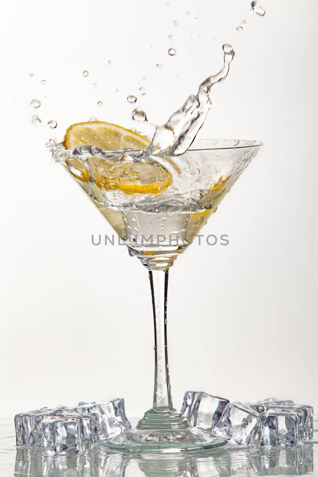 Glass of water, lemon and watersplashes on a black studio background