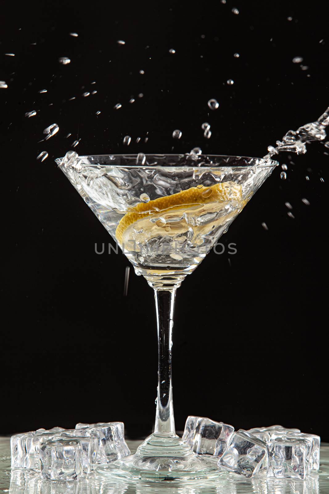 Glass of water, lemon and watersplashes on a black studio background