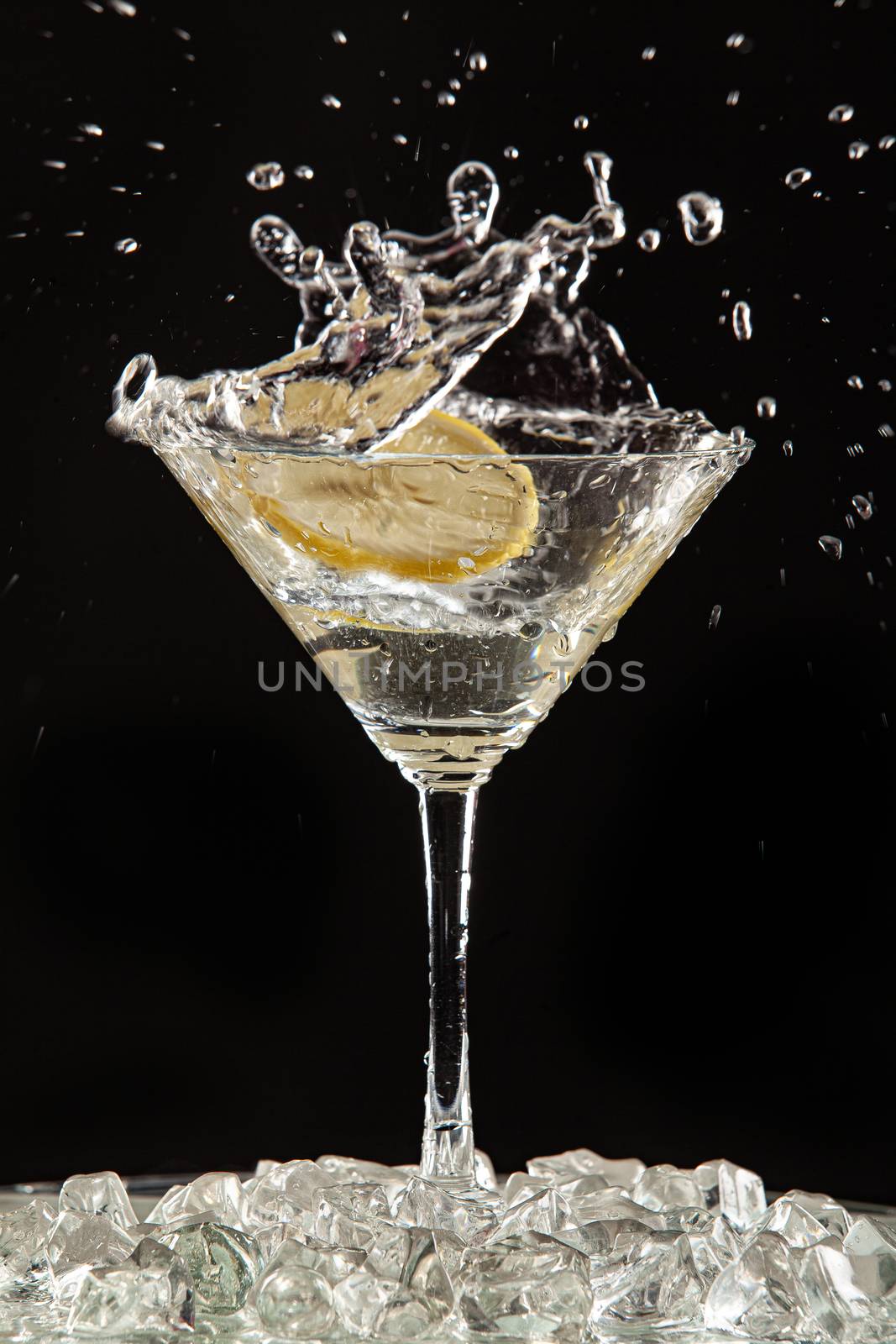 Glass of water, lemon and watersplashes on a black studio background