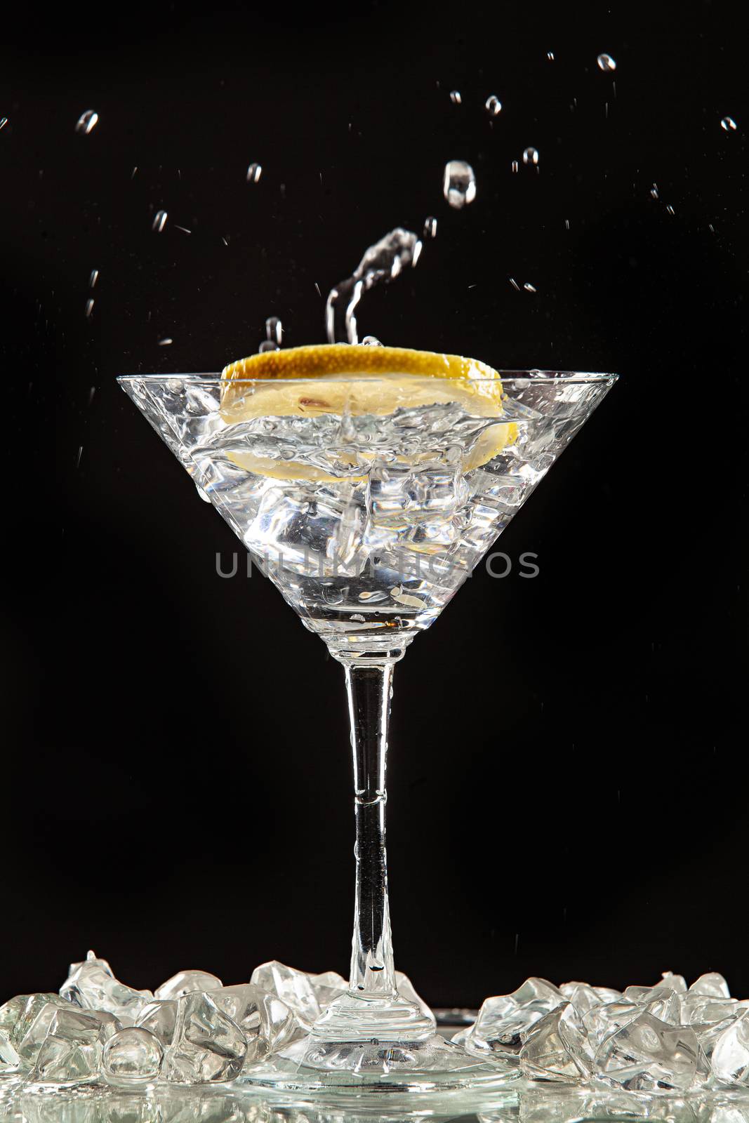 Glass of water, lemon and watersplashes on a black studio background