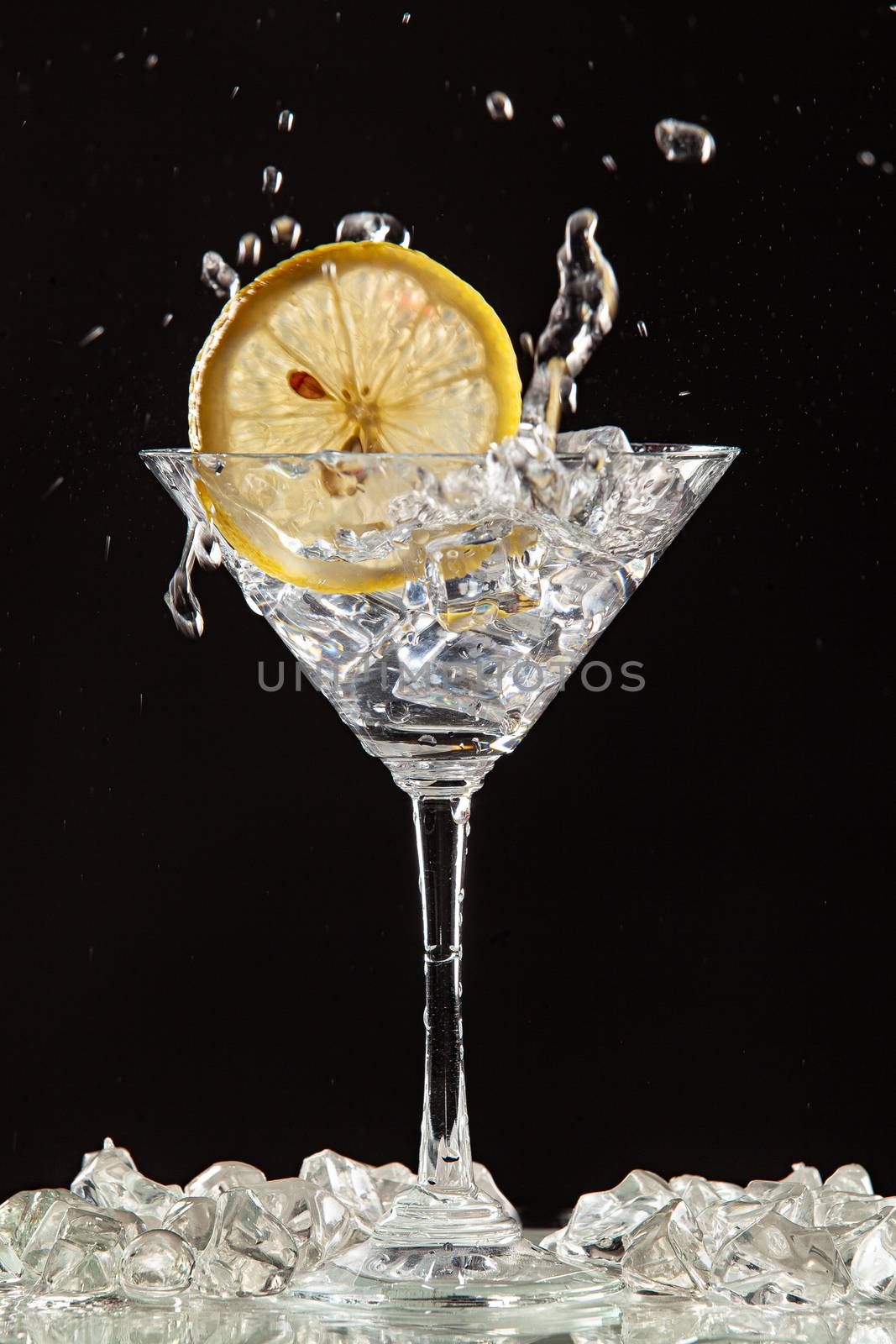 Glass of water, lemon and watersplashes on a black studio background