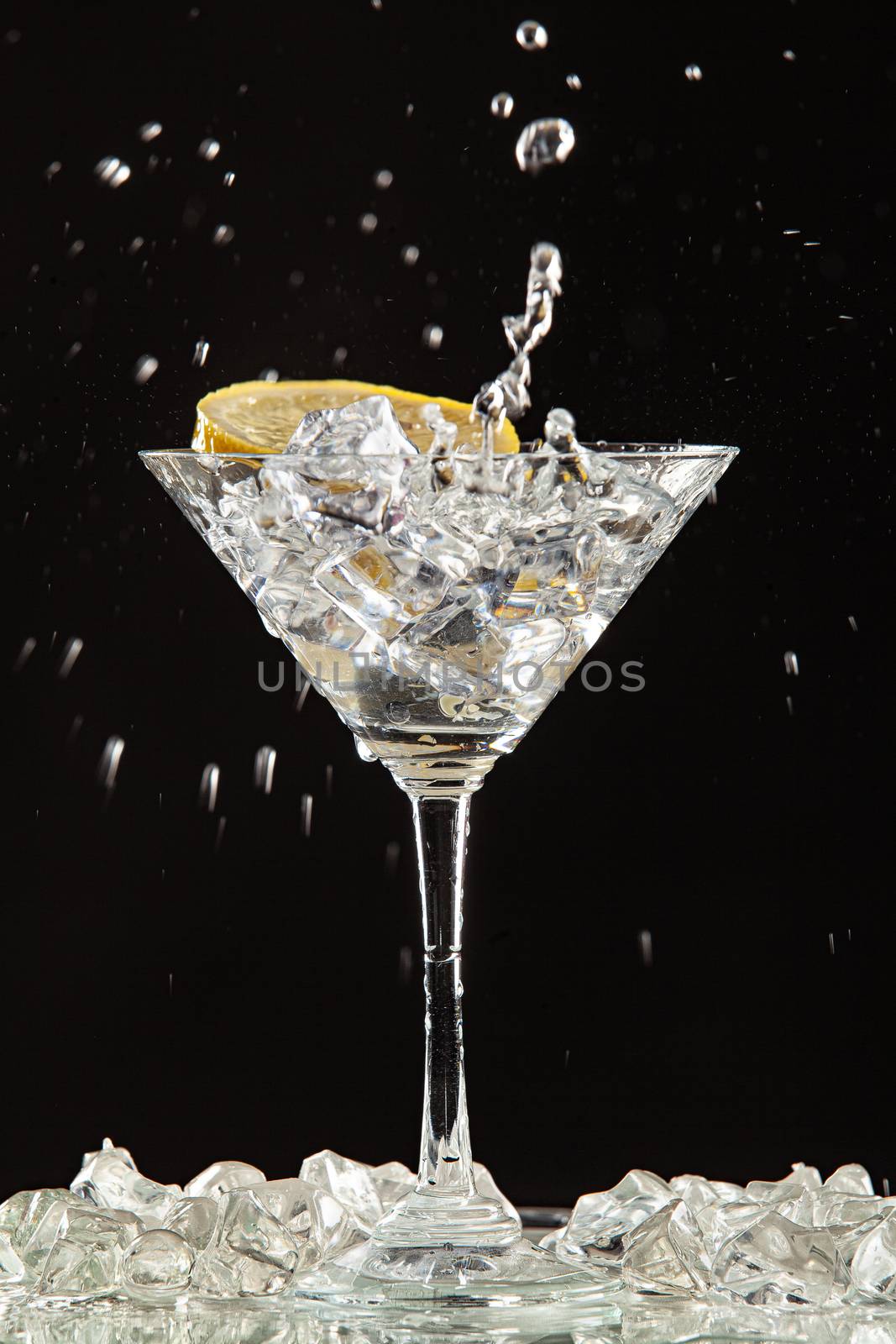 Glass of water, lemon and watersplashes on a black studio background