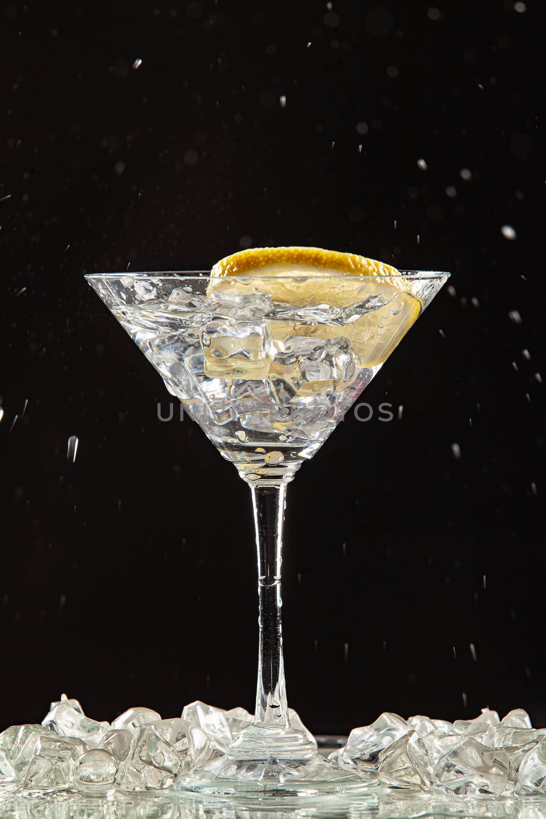 Glass of water, lemon and watersplashes on a black studio background