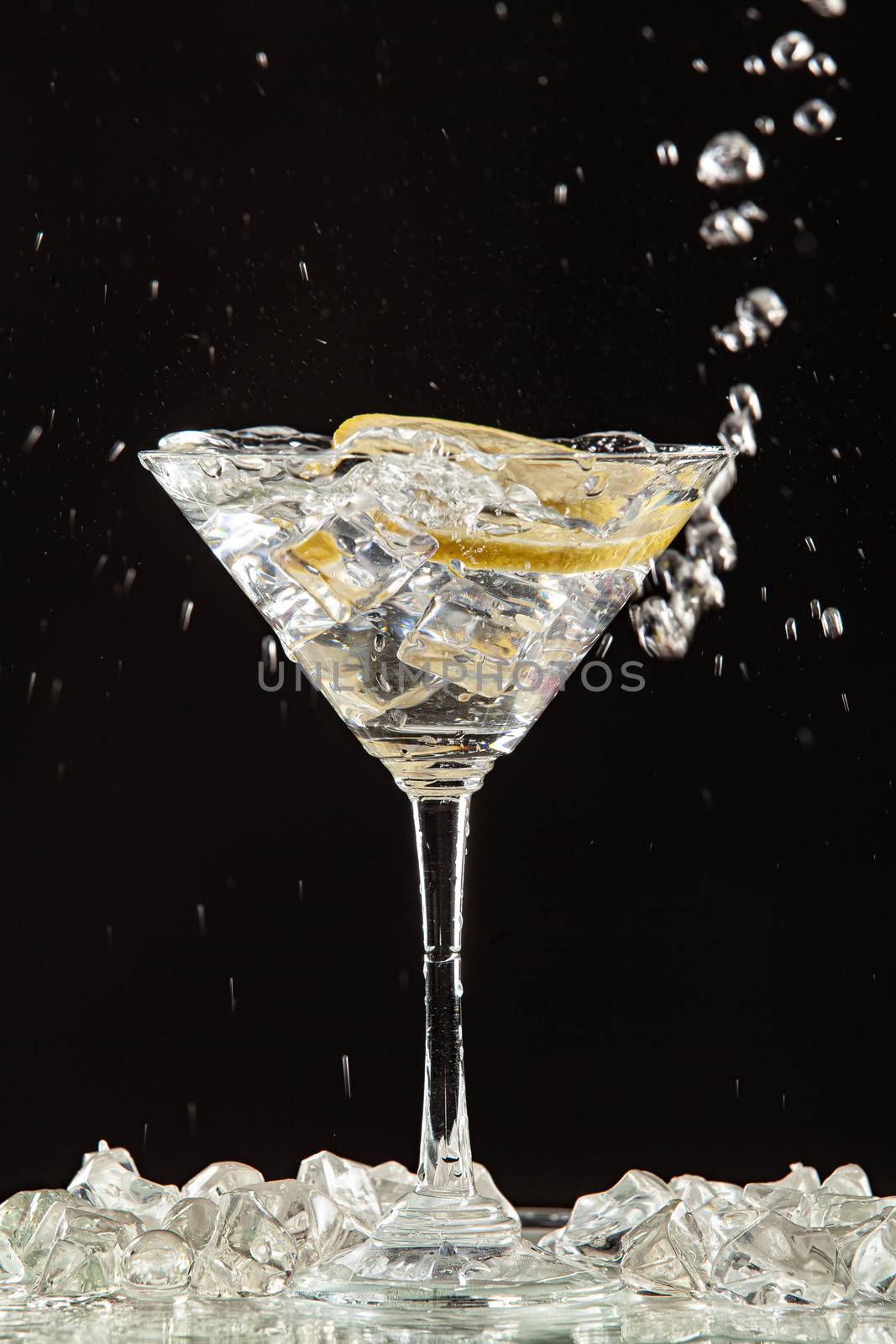 Glass of water, lemon and watersplashes on a black studio background