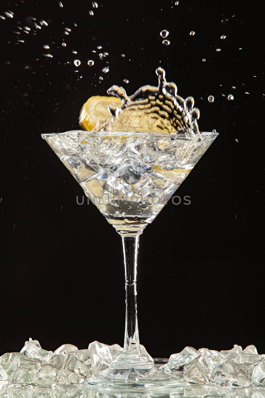 Glass of water, lemon and watersplashes on a black studio background
