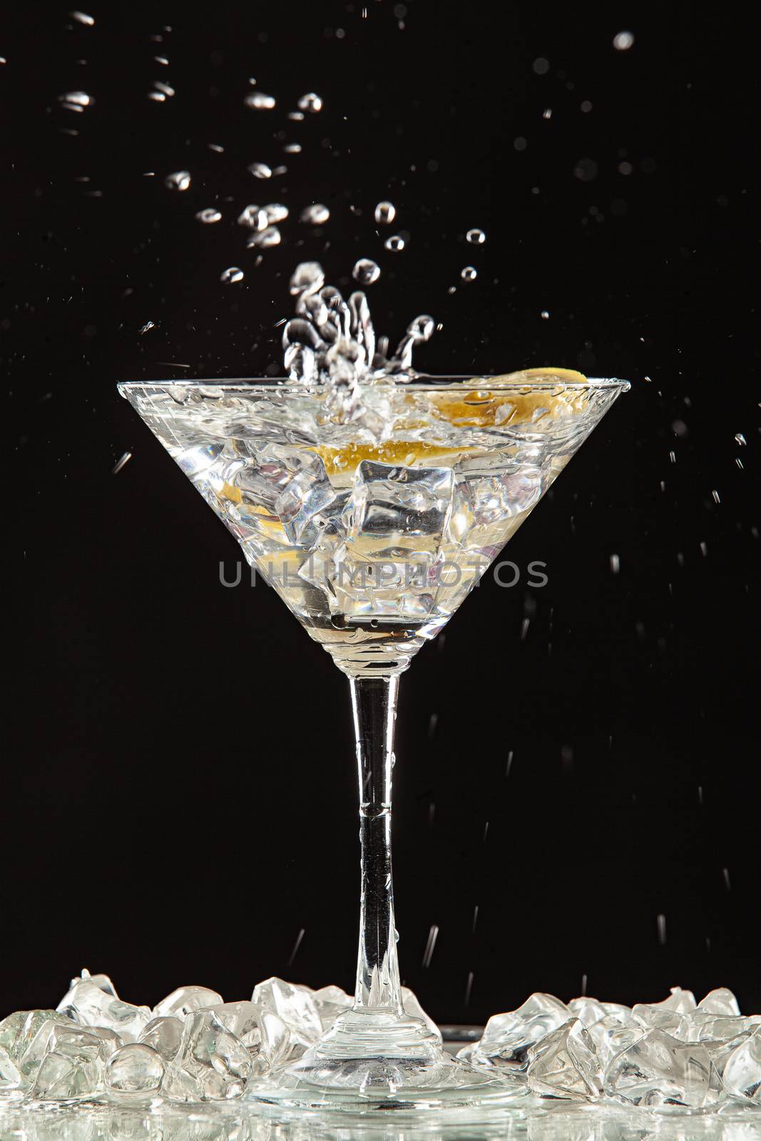 Glass of water, lemon and watersplashes on a black studio background