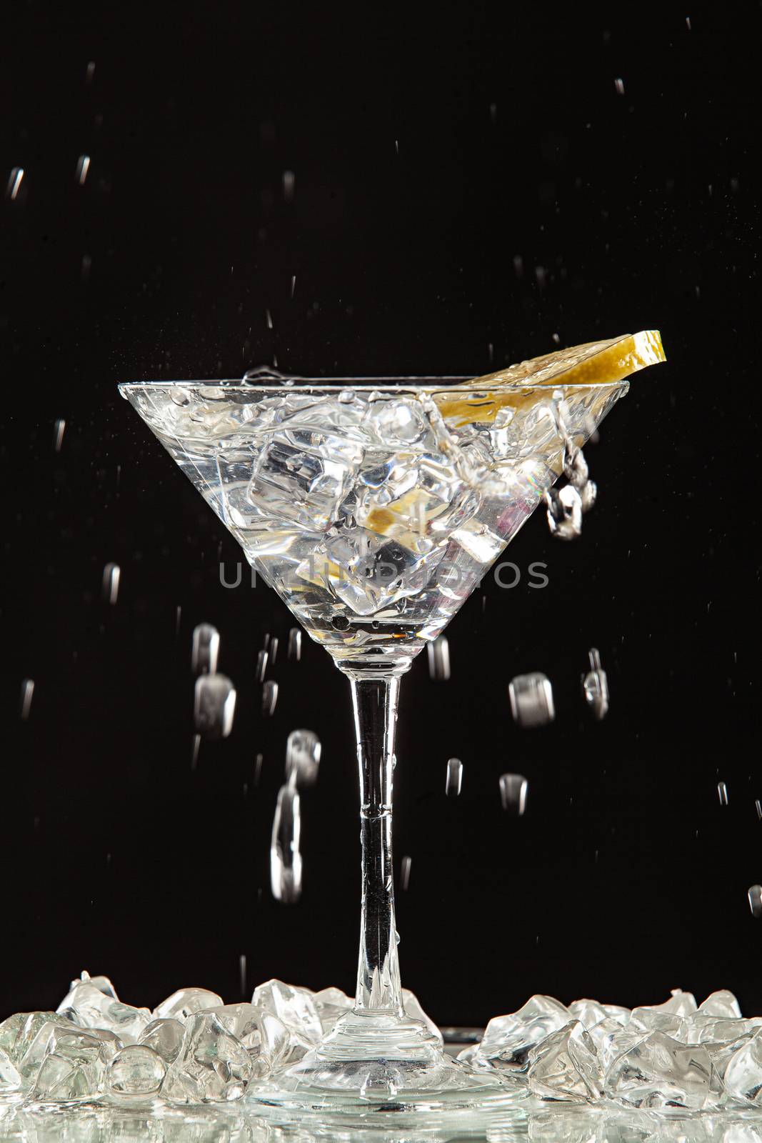 Glass of water, lemon and watersplashes on a black studio background