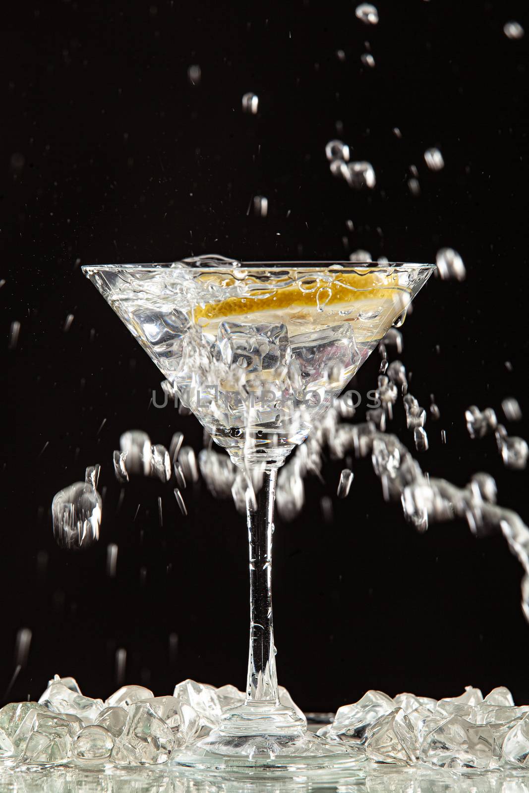 Glass of water, lemon and watersplashes on a black studio background