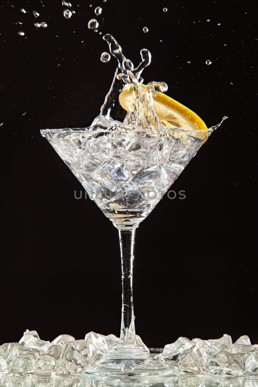 Glass of water, lemon and watersplashes on a black studio background
