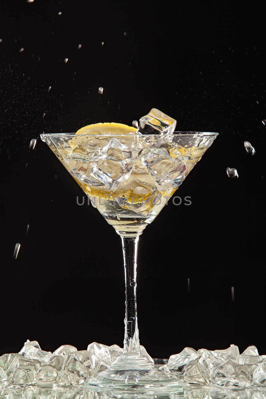 Glass of water, lemon and watersplashes on a black studio background
