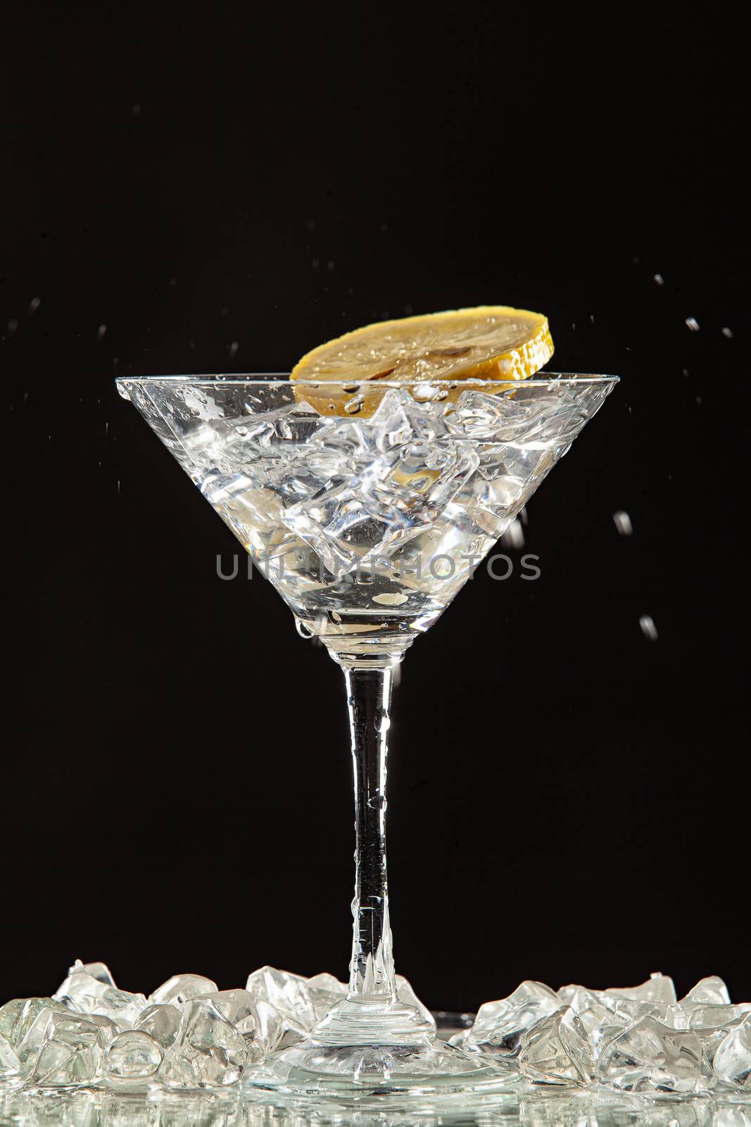 Glass of water, lemon and watersplashes on a black studio background