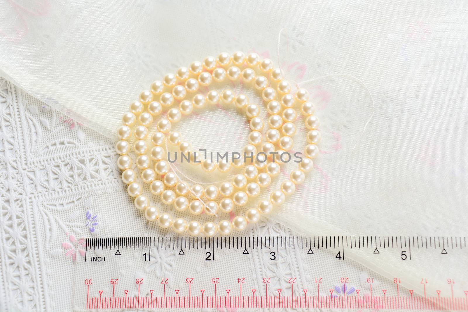 pearl necklace on white fabric background, Close up shot of glas by yuiyuize