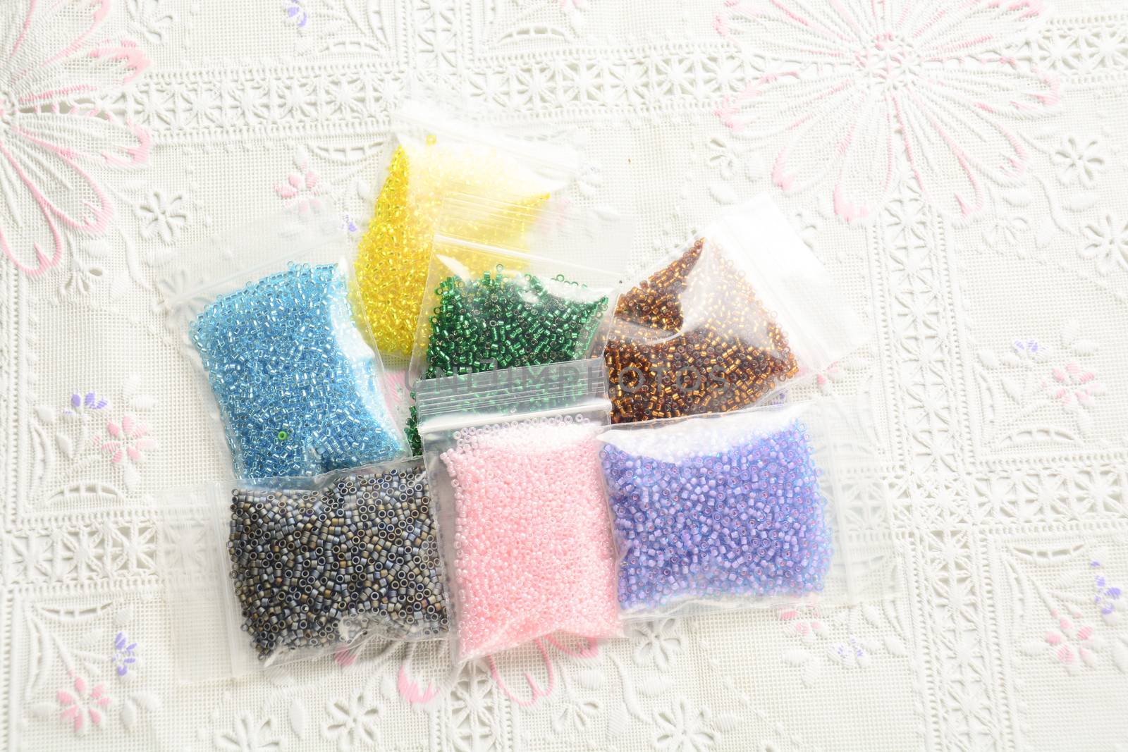 Colorful beads on white fabric surface. Various of shapes and colors to make jewelry
