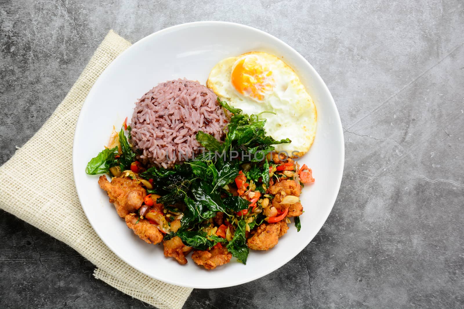 Crispy chicken cooked with green basil, served with steamed rice and fried egg, hot and spicy dish with basil leaves.
