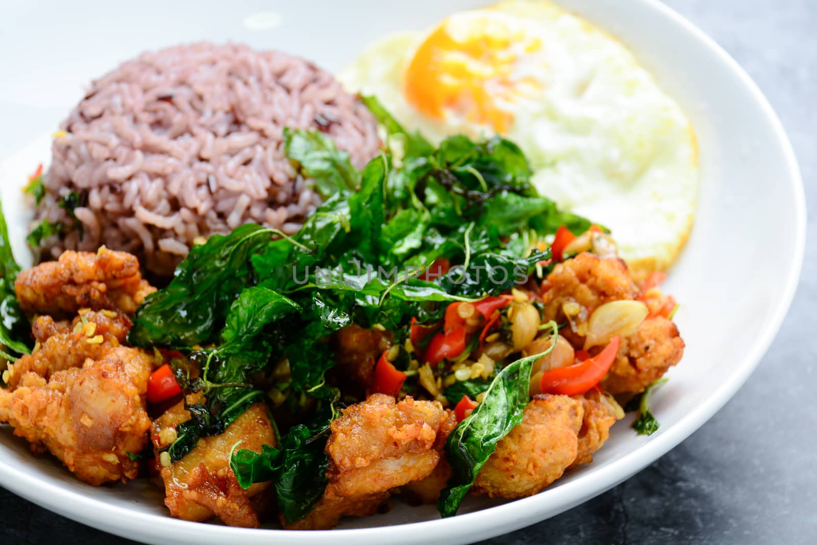 Crispy chicken cooked with green basil, served with steamed rice and fried egg, hot and spicy dish with basil leaves.
